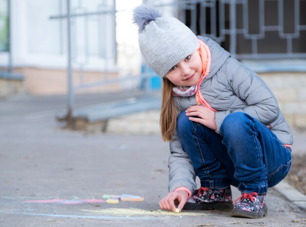 Little girl drawing on asphalt