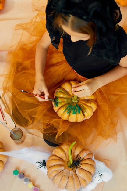 사진 오렌지색 할로윈 jackolantern 호박에 얼굴을 그리는 작은 소녀 행복한 아이가 집에서 호박을 장식하는 휴일 장식 개념