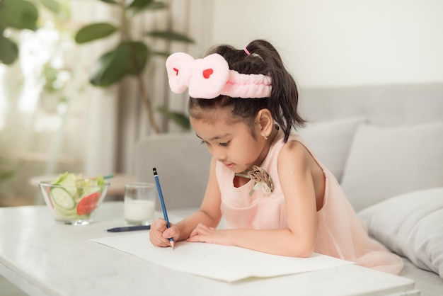 Little girl drawing picture at table with painting tools indoors