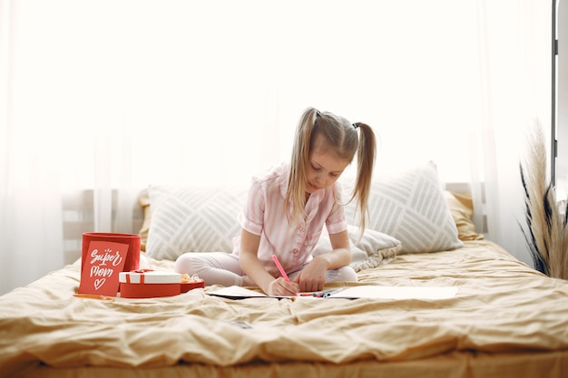 Little girl drawing sitting on bed with presents