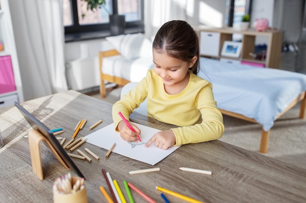 家で色筆で絵を描く小さな女の子