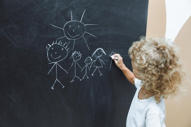 Photo little girl draws a family on a chalkboard