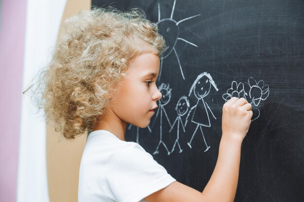 Little girl draws a family on a chalkboard