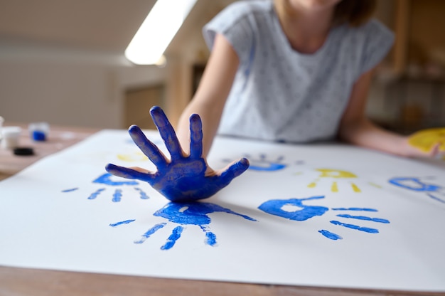 Little girl draws a handprint, kid in workshop
