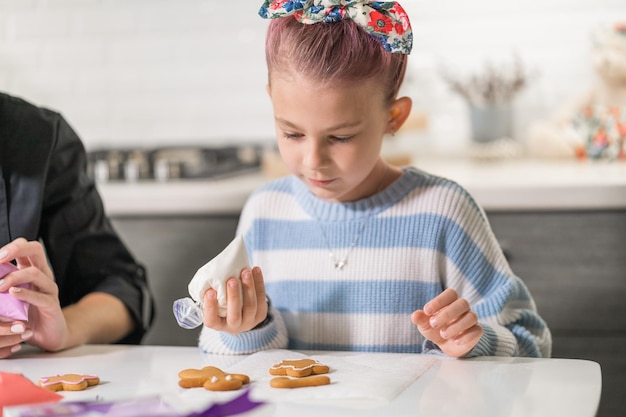 Little girl draws a pattern on cookies Cookie master class