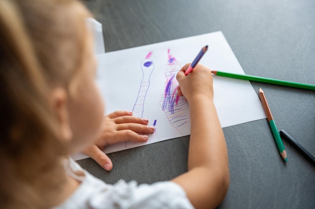 Photo little girl draws with colored pencils in home