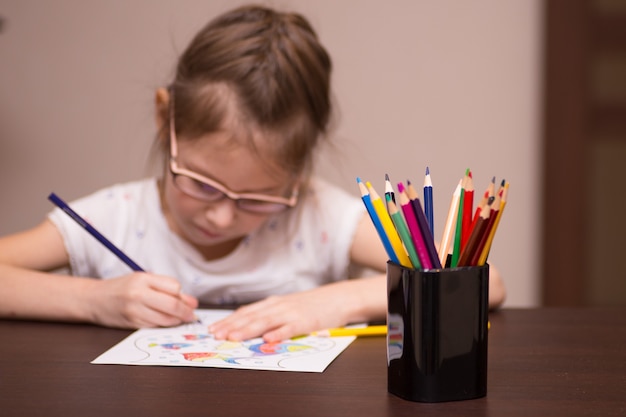 Маленькая девочка рисует цветными карандашами
