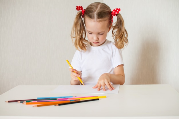 Little girl draws with crayons. Home schooling