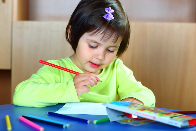 Little girl draws with crayons