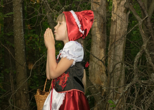 Маленькая девочка, одетая как Красная Шапочка в весеннем лесу
