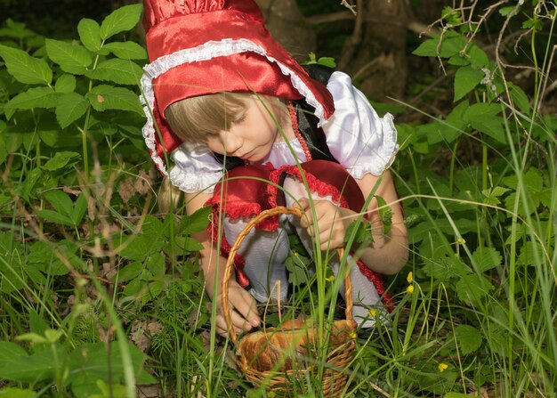 Foto bambina vestita da cappuccetto rosso nella foresta di primavera