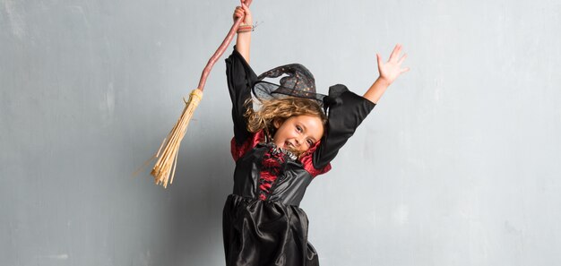 Little girl dressed as a witch for halloween holidays jumping