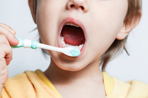 Little girl dressed in bathrobe brushing her teeth