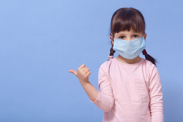 Little girl dresses medical protective mask and rose shirt, posing