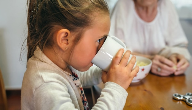 祖母と一緒にミルクを飲む少女