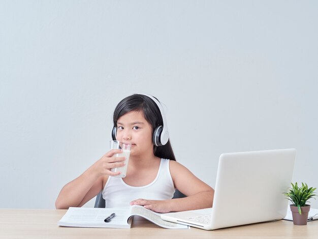 Little girl drinking milk while studying