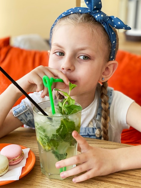 Little girl drinking non-alcoholic mojito  in a cafe