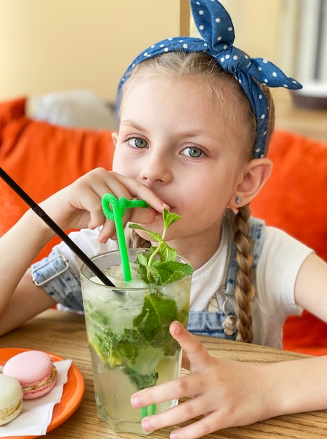 Little girl drinking non-alcoholic mojito  in a cafe