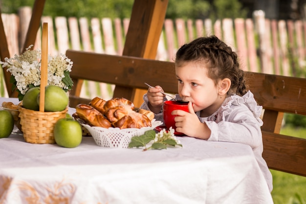 little girl drinking tea with buns