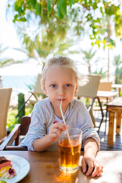 Little girl drinks the juice on the street.