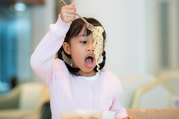 小さな女の子がインスタントヌードルを食べる