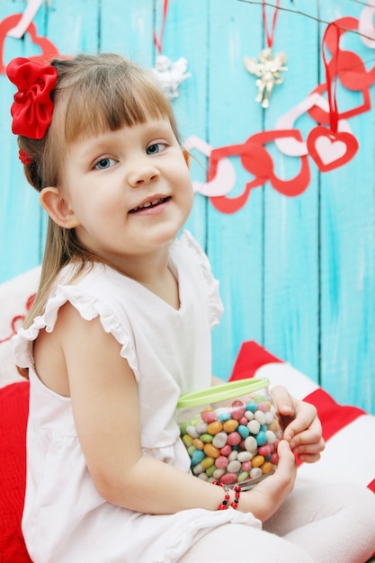 Маленькая девочка ест конфеты из фляги