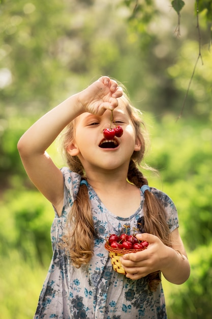 little girl eating cherries from a basket on nature