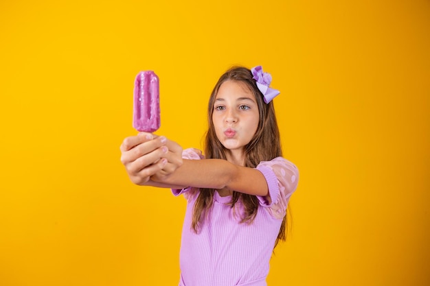 Bambina che mangia un ghiacciolo congelato colorato in estate. ragazza con un ghiacciolo