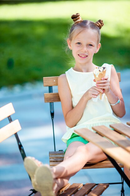 Little girl eating ice-cream outdoors at summer in outdoor cafe