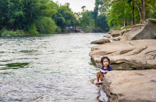 Little girl eating near the river