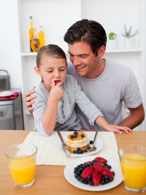 Photo little girl eating strawberries with her father