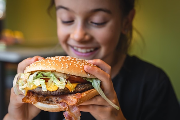 A little girl eats an appetizing burger closeup