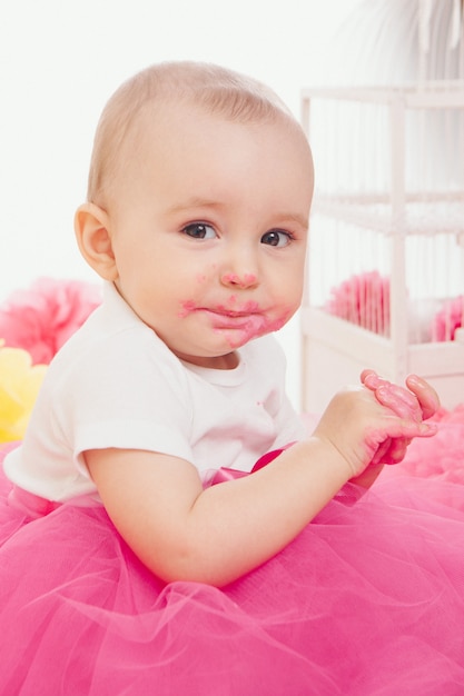 A little girl eats cake with her hands. The baby was covered in food. birthday party