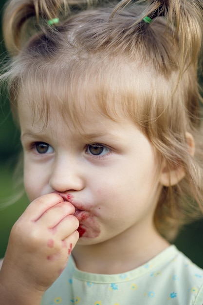 The little girl eats cherry in the garden. Summer