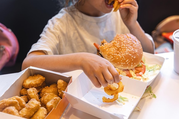 小さな女の子がカフェでファーストフードを食べる