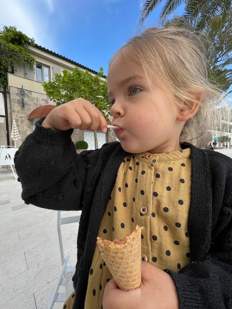 Little girl eats ice cream with a spatula from a waffle cup