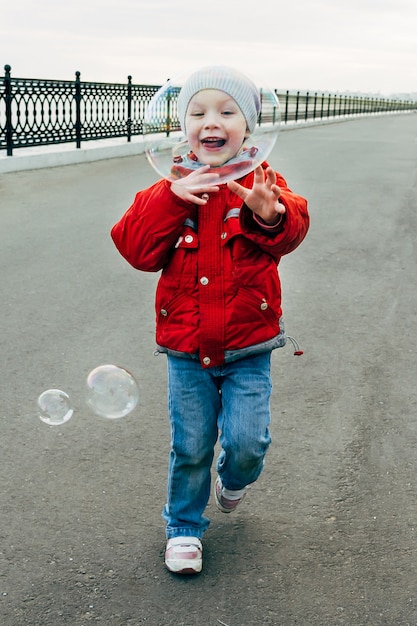 Маленькая девочка ест мыльные пузыри на набережной