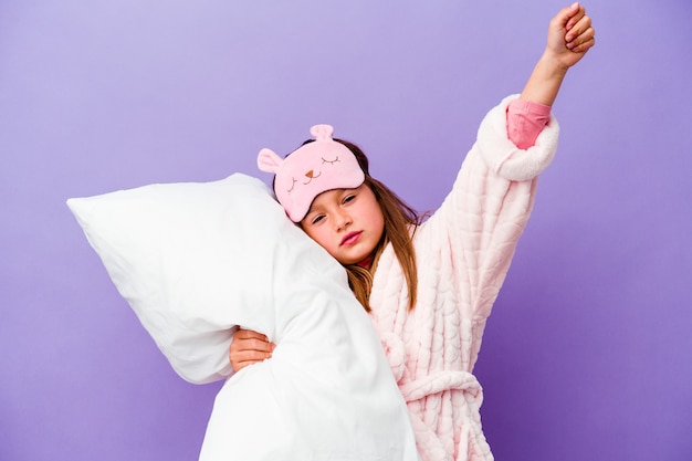 little girl embracing a pillow happy isolated on purple wall