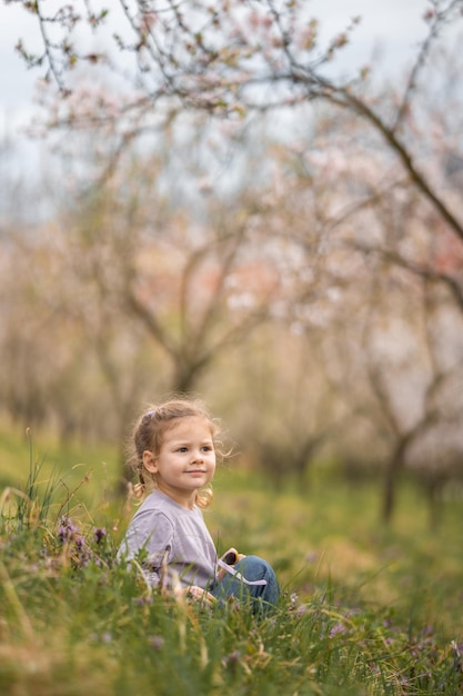 Little girl enjoying nice and sunny spring day near blooming apple tree in prague park