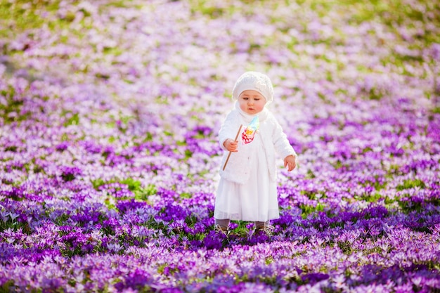 Little girl enjoying spring and sun among the spring flowers crocuses