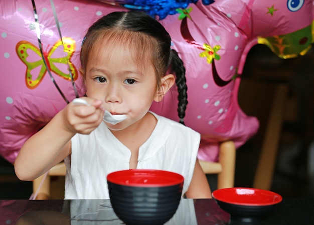 小さな女の子が日本のレストランで味噌汁を食べる