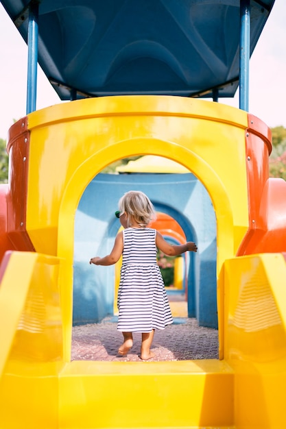 Little girl entered the toy house on the playground back view