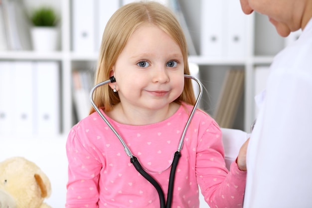 Little girl examining her doctor by stethoscope Health care childpatient trust concept