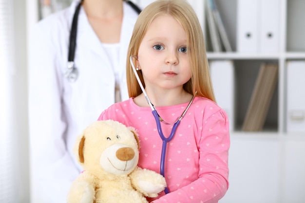 Little girl examining her Teddy bear by stethoscope Health care childpatient trust concept