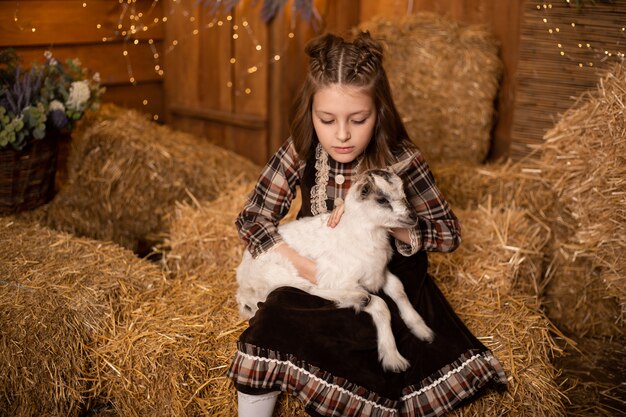 Little girl farmer taking care of cute goat baby at the barn in farm