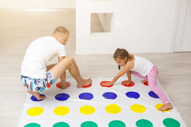 little girl and father play twister at home