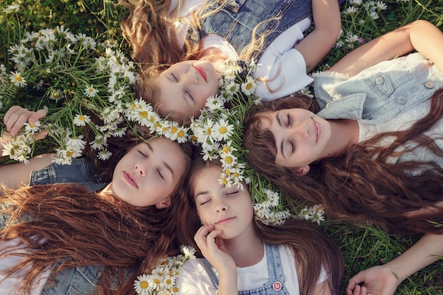 Little girl in a field of daisy flowers. Girls in a wreath of white daisies, the concept and idea of a happy childhood