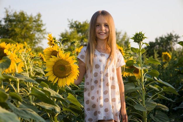 Little girl on the field with sunflowers blurred background