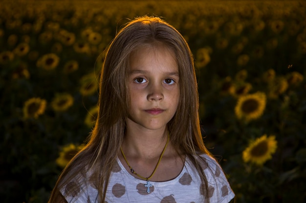 Little girl on the field with sunflowers blurred background