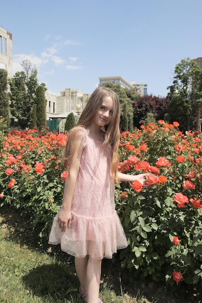 Little girl among flowerbed of orange roses